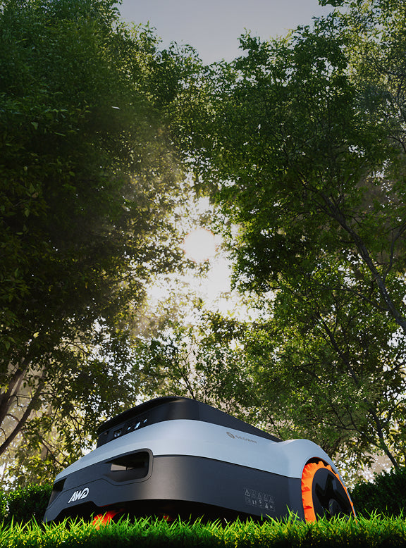 Segway Navimow i105E Mähroboter mäht den Rasen unter dichten Bäumen.